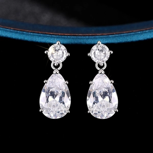 Détail macro de boucles d'oreilles argentées en goutte avec cristaux étincelants