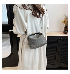 Grey pleated bucket bag styled with a white trench coat in a modern minimalist indoor setting