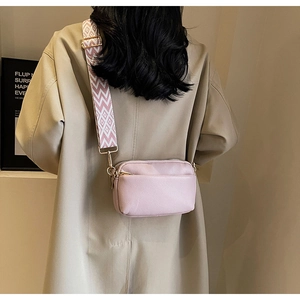 Rear view of a pink PU leather crossbody bag with a wide patterned strap and gold hardware