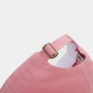Detailed view of pink cotton baseball cap with adjustable bronze metal buckle strap