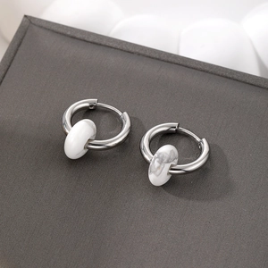 Detail of silver stainless steel hoop earrings with white marble stone charms