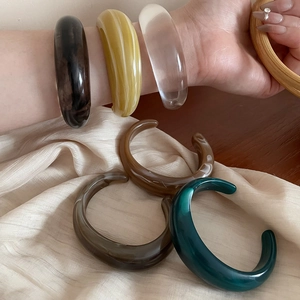 Macro shot of assorted colorful acrylic bangles in amber and emerald tones with smooth finish