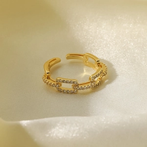 Macro detail of 18K gold-plated chain ring with micro-pave zircons on silk background