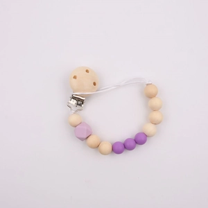 Detail of wooden baby pacifier clip with purple silicone beads on white background