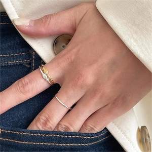 Primo piano di anelli a forma di pesce in argento 925 e oro indossati su denim