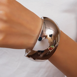 Close-up of a wide silver cuff bracelet with a mirror-polished finish on a white background