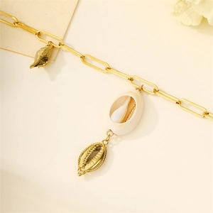 Detailed close-up of golden paperclip chain bracelet with natural seashell charms