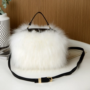 Detailed view of white faux fur handbag with golden zipper and black leather straps