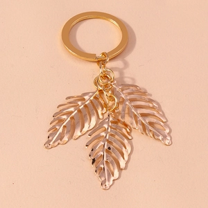 Detailed view of three golden hollow leaf pendants attached to a polished metal keychain