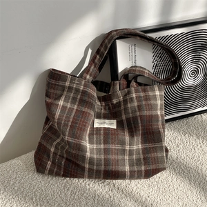 Detailed close-up of retro plaid wool tote bag on soft blanket with natural lighting