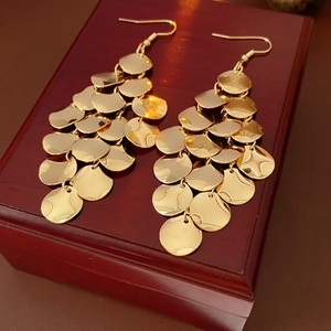 Detailed shot of golden sequin fringe earrings resting on a vintage wooden jewelry box