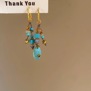 Detail of ethnic fish shell tassel earrings with turquoise beads and gold hooks