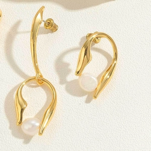 Detailed view of golden irregular metal frame earrings with white baroque pearls