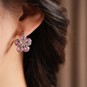 Gros plan de boucles d'oreilles fleur en zircon rose sur un modèle au style élégant