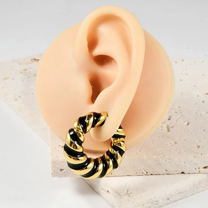 Detailed view of twisted gold and black enamel earring on silicone ear model
