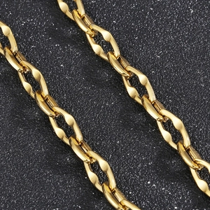 Close-up of golden lip chain necklace made of stainless steel on a dark textured surface