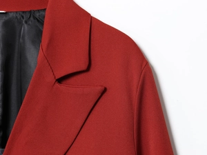 Detailed view of dark red blazer collar and shoulder with fine fabric texture and black lining