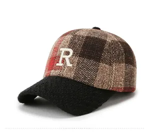Detail view of red brown plaid cap with black textured brim and white letter R embroidery