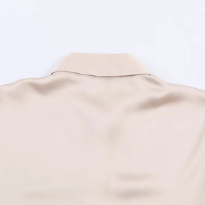 Detail view of champagne satin fabric with smooth silk texture on shirt collar and back