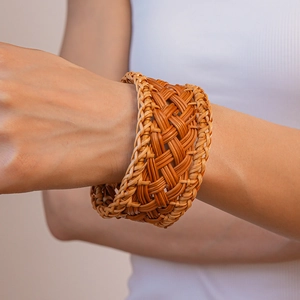 Close-up of handmade woven rattan wide cuff bracelet with natural geometric texture