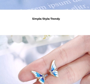 Macro shot of blue gradient enamel butterfly stud earrings with delicate gold plating