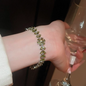 Macro shot of 18k silver plated bracelet with olive green heart stones and flower motif