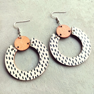 Detail of bohemian wood earrings with black dot pattern on white circular pendant