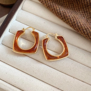 Detail view of 18k gold plated resin square earrings on a cream jewelry box