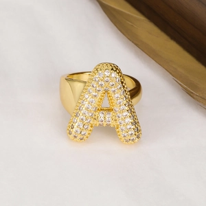 Anello aperto lettera A dorato con pavé di zirconi su sfondo chiaro testurizzato