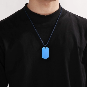 Close-up of blue dog tag pendant with matching metal chain worn by a male model