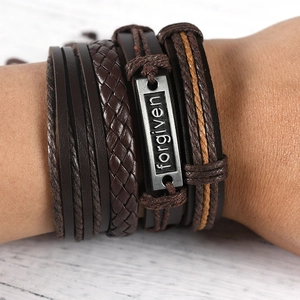 Macro shot of dark brown braided leather bracelets with engraved forgiven metal plate