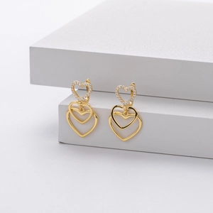 Detailed macro view of nested golden heart drop earrings with sparkling zircon inlay