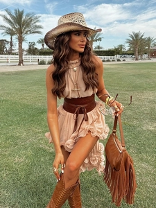 Detail of bohemian pink chiffon dress with ruffles, brown leather belt and tassel bag