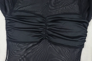 Detail of black ruched satin and sheer mesh patchwork on this chic long-sleeved mini dress