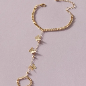 Bracelet bague papillon doré avec chaîne à maillons et pendentifs sur fond rose