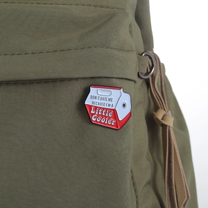 Detail of a milk cooler enamel pin with humorous text on a green canvas bag