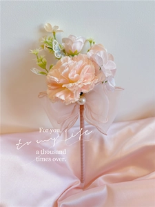 Detail of pink carnation and rose flower pen with ribbon bow and pearls on silk