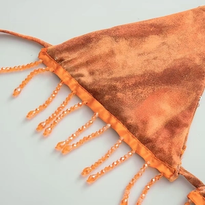 Detailed close-up of orange tie-dye velvet fabric with transparent beaded fringe tassels