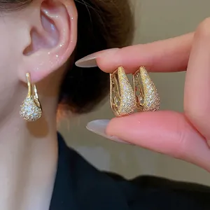 Élégantes créoles dorées en forme de U avec zircons sertis sur un modèle féminin