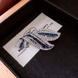 Macro detail of silver-tone brooch with blue zircon and pavé crystals in a jewelry box