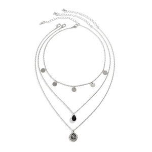 Detail of silver layered necklace with black teardrop pendant and engraved coin medallion