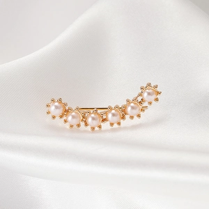 Elegant close-up of gold-toned ear cuff with small pearls on white silk background