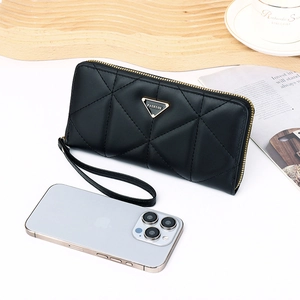 Close-up of black quilted leather long wallet with gold zipper and metal logo plate