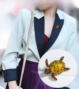 Detailed close-up of a turtle brooch featuring green enamel and red crystal rhinestones