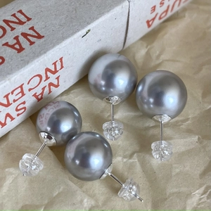 Two pairs of silver gray pearl stud earrings with silicone backs on vintage paper