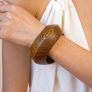 Macro detail of wide wood-textured bangle with brown grain worn on model wrist