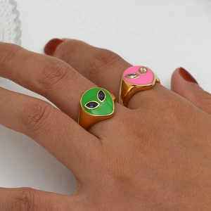 Detailed macro view of gold plated alien rings with colorful enamel and gem eyes