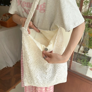 Détail du sac cabas en dentelle blanche avec motif floral et fermeture à boucle magnétique