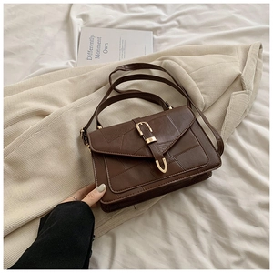 Détail du sac bandoulière vintage marron avec boucle en U dorée et texture cousue