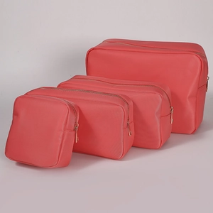 Set of four coral red nylon makeup bags with gold zippers in various sizes for travel
